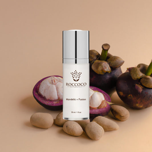 White bottle of Roccoco Botanicals Mandelic + Fusion treatment on tan background with botanical ingredients