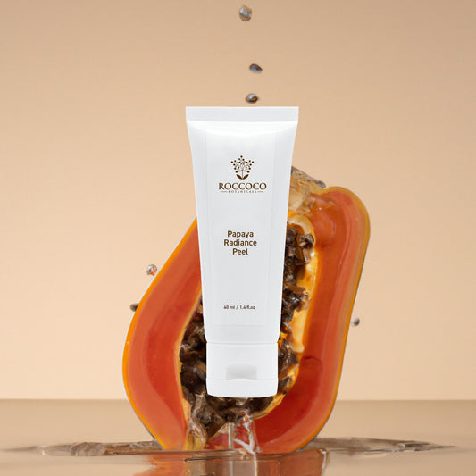 White tube of Roccoco Botanicals Papaya Radiance Peel on tan background with a papaya and water droplets