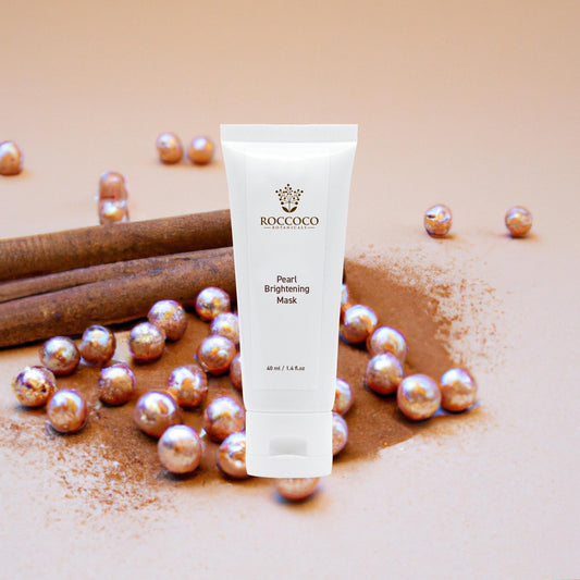 White tube of Roccoco Pearl Brightening Mask with a tan background, pearls and cinnamon