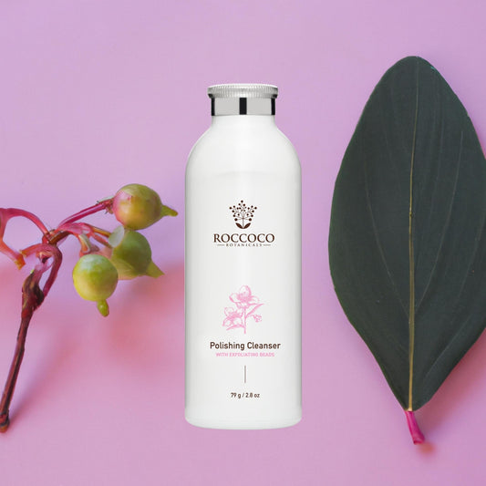 Bottle of Roccoco Polishing Cleanser on a pink background with botanicals